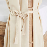 A Hampton Cotton Voile Curtain, in beige and part of a set of 6, elegantly ties around a wooden bedpost, evoking the look of neutral canopy bed curtains.