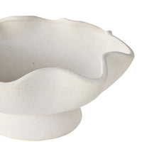 The Tranquil Wavy Pedestal Bowl features a wide, wavy rim and a white sand clay finish, elegantly displayed on a pedestal base to create a stunning decorative centrepiece against a white background.